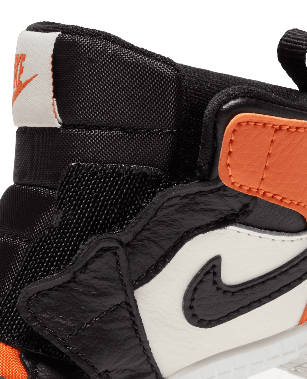 Detail of the Nike Jordan 1 Crib Bootie ankle collar in Sail, Black, and Starfish orange leather.